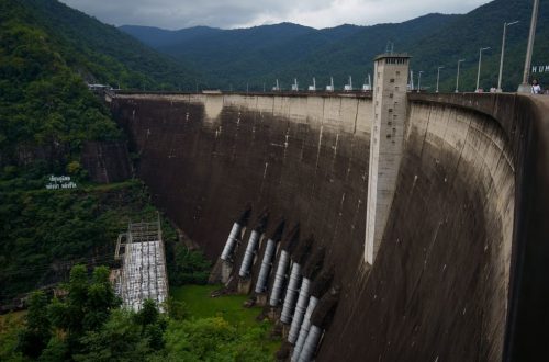 Bhumibol Dam in Ban Na, Tak, Thailand, surrounded by lush greenery and mountains.