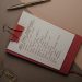 Top view of notebook with handwritten New Year's resolutions, pen, and clips on a desk.