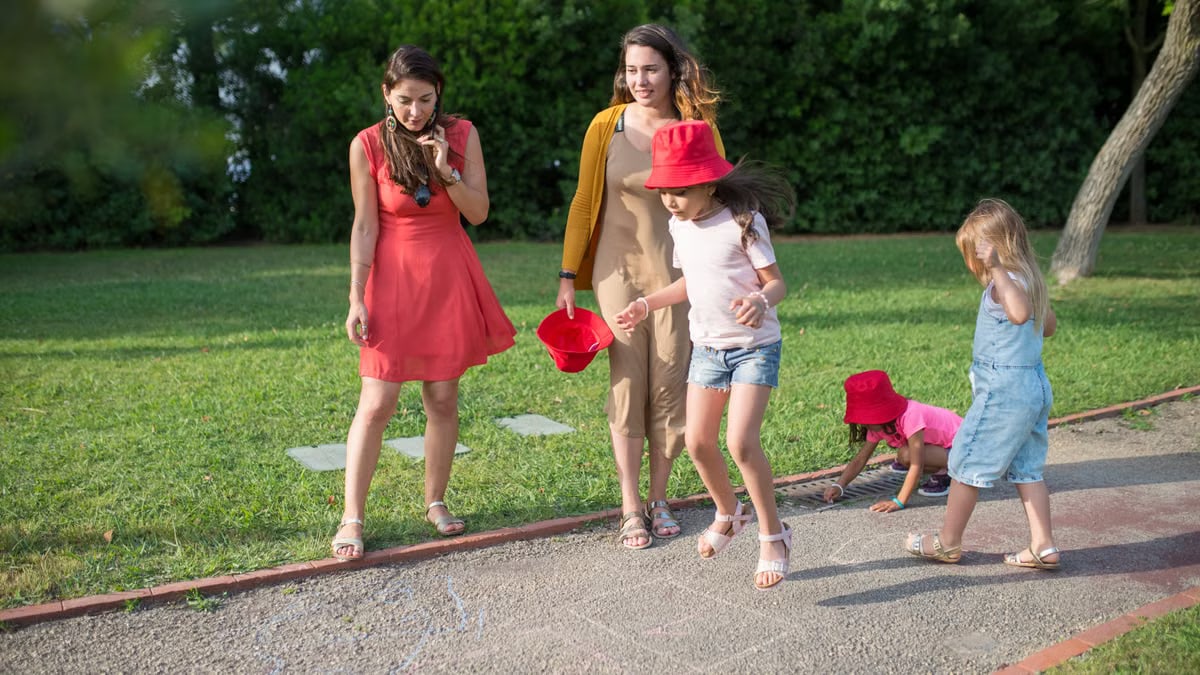 A joyous family experience in a lush Portugal park, featuring playful activities between young girls and adults.